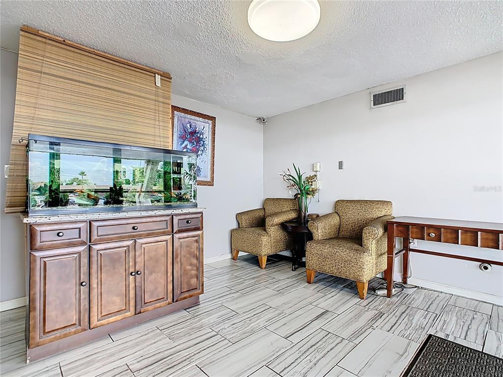 A room features a large fish tank on a wooden cabinet, two armchairs, and tile flooring — 4121 W VINE STREET, KISSIMMEE, FL
