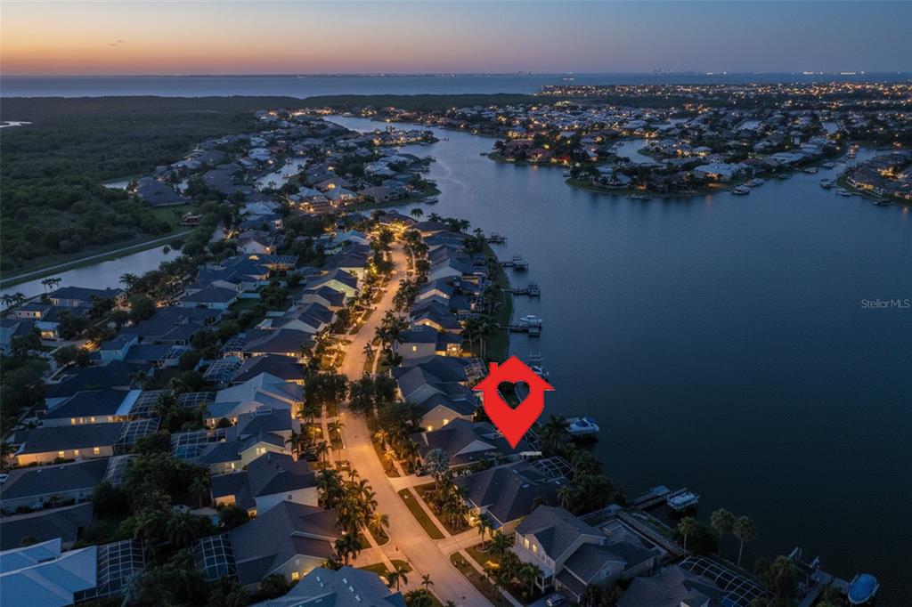 An aerial view shows a waterfront residential neighborhood at dusk with a highlighted house — 5229 BRIGHTON SHORE DRIVE, APOLLO BEACH, FL