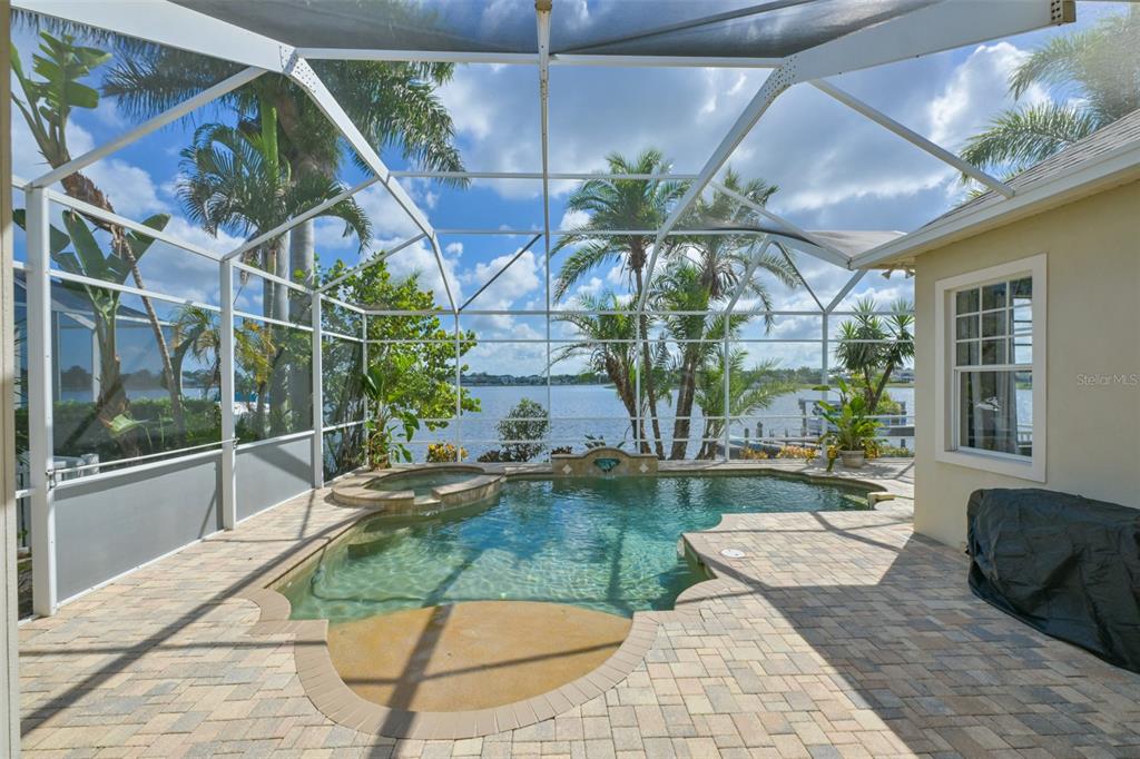 A screened-in pool patio features a hot tub and views of a waterfront canal — 5229 BRIGHTON SHORE DRIVE, APOLLO BEACH, FL