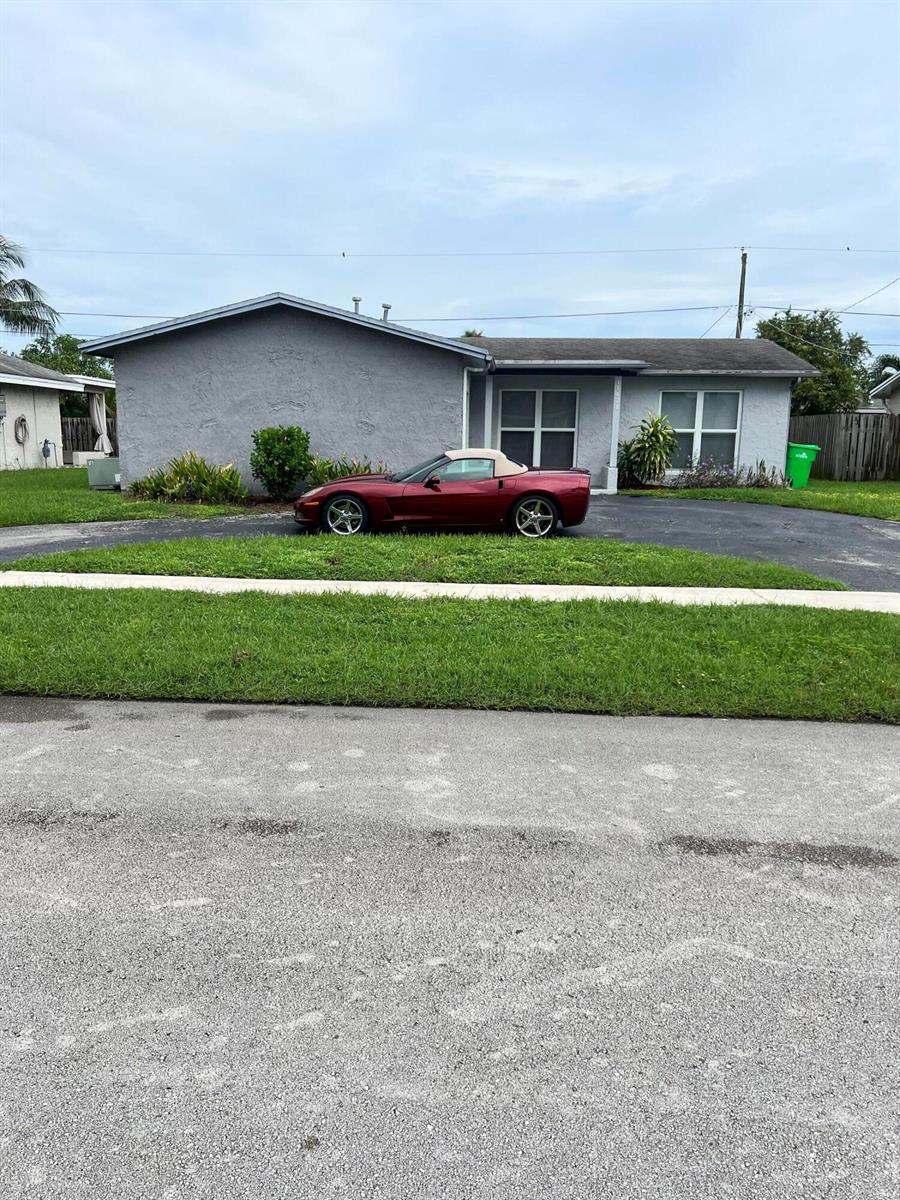 A single-story gray house with a red convertible parked in the driveway — 11421 NW 39th Place, Sunrise FL 33323, SUNRISE, FL
