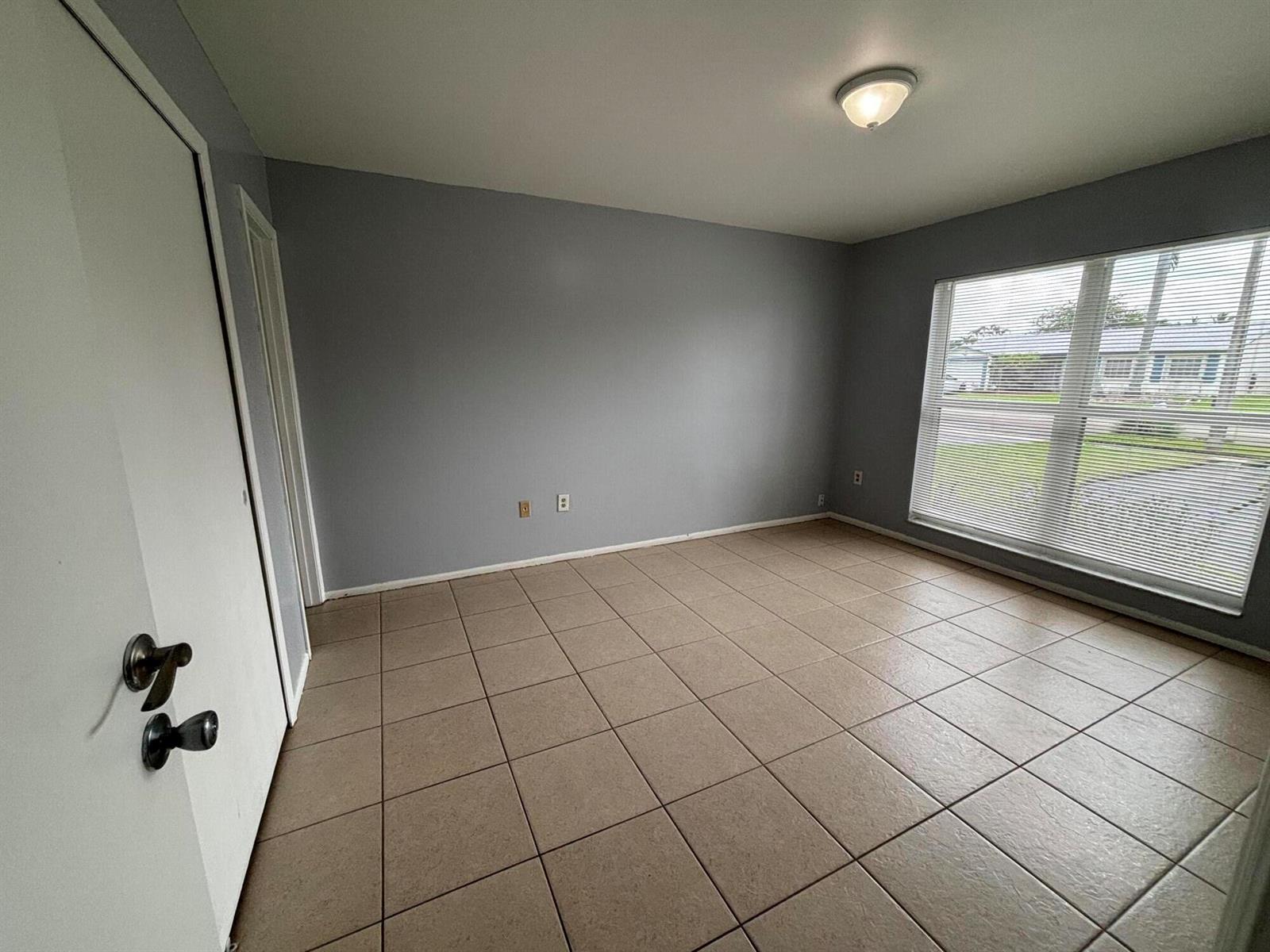 An empty room with gray walls, tan tile flooring, and a large window with blinds — 11421 NW 39th Place, Sunrise FL 33323, SUNRISE, FL