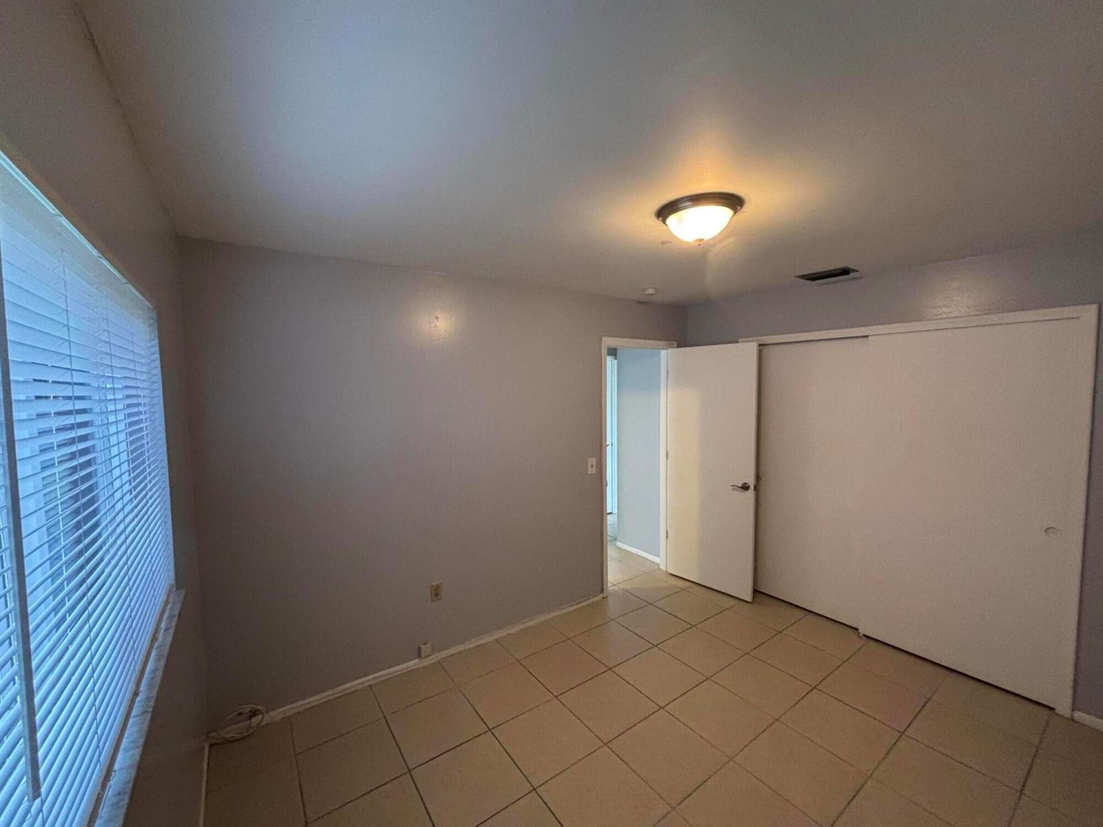 A bedroom features light gray walls, tile flooring, a ceiling light, and a sliding closet — 11421 NW 39th Place, Sunrise FL 33323, SUNRISE, FL