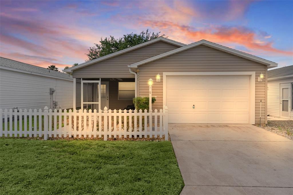 A tan single-story house with a white picket fence and a one-car garage — 8201 SE 169TH PALOWNIA LOOP, THE VILLAGES, FL