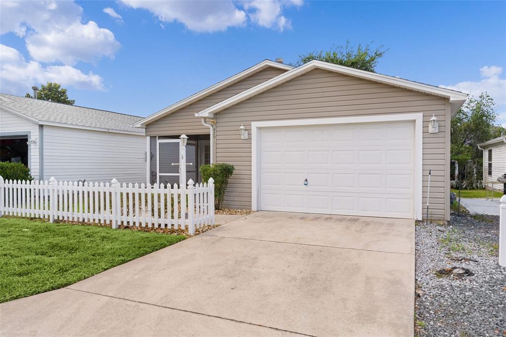 A single-story house with tan siding, a white garage door, and a white picket fence — 8201 SE 169TH PALOWNIA LOOP, THE VILLAGES, FL