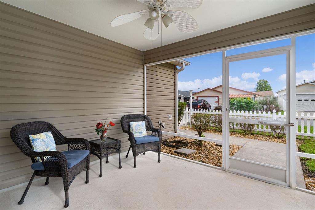 A screened-in porch features two wicker chairs, a small table, and a ceiling fan — 8201 SE 169TH PALOWNIA LOOP, THE VILLAGES, FL