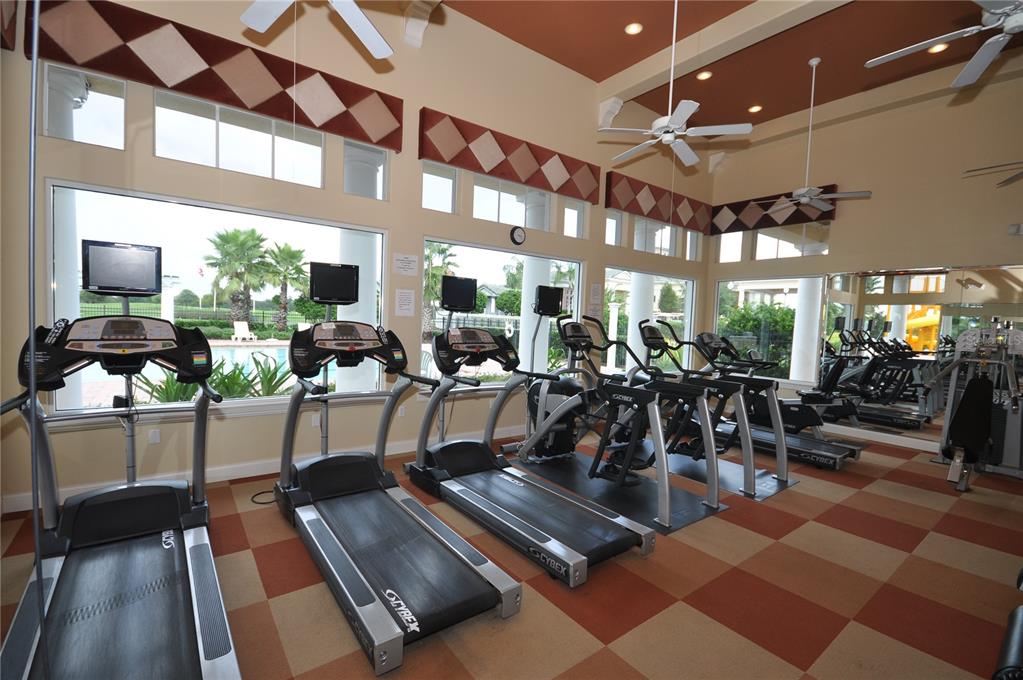 A fitness center features multiple treadmills, large windows, ceiling fans, and a checkered floor pattern — 5558 LEWISHAM DRIVE, DAVENPORT, FL