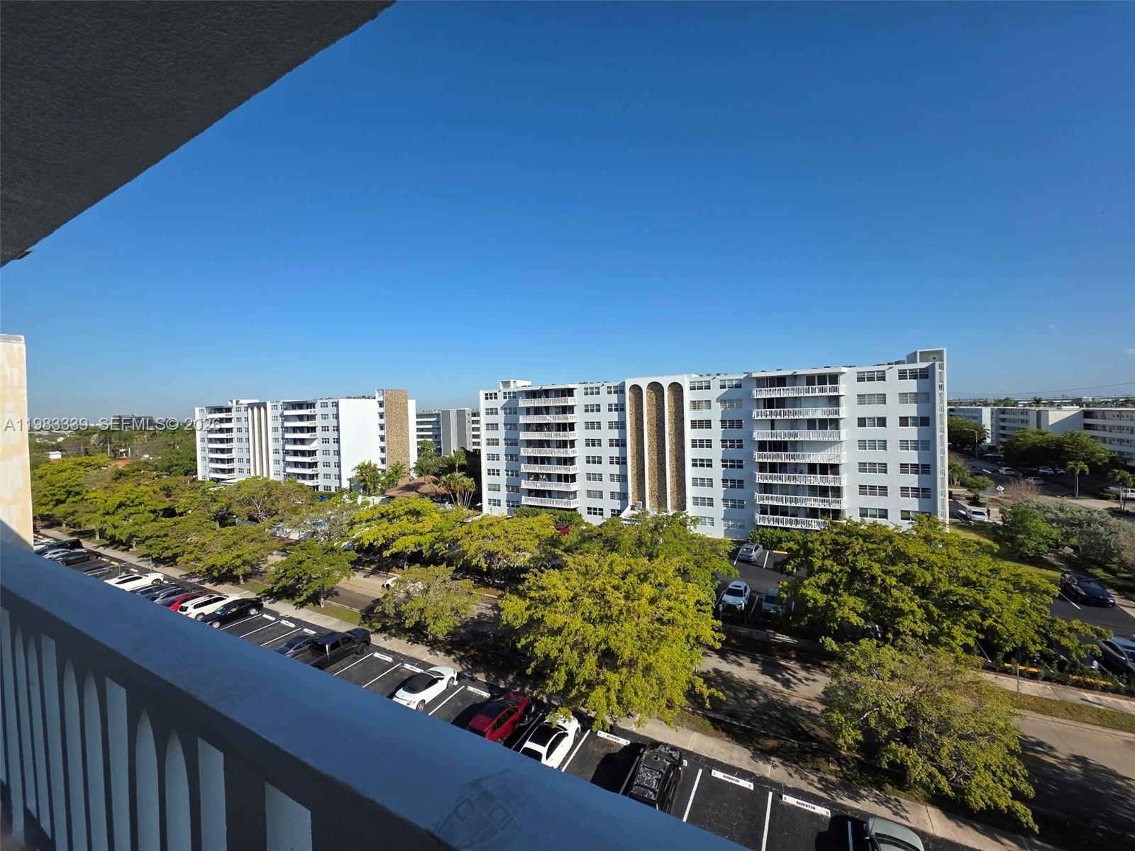 A high-angle view shows a parking lot and trees between two large apartment buildings — 319 NE 14th Ave # 702, Hallandale Beach FL 33009, HALLANDALE BEACH, FL