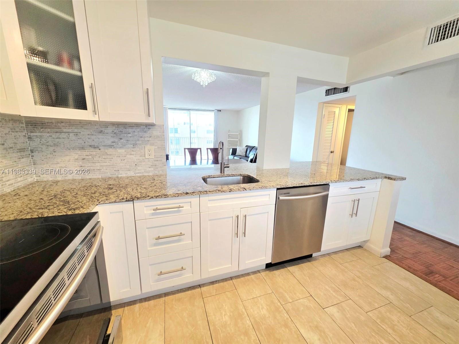 A kitchen features white cabinets, granite countertops, stainless steel appliances, and light tile flooring — 319 NE 14th Ave # 702, Hallandale Beach FL 33009, HALLANDALE BEACH, FL