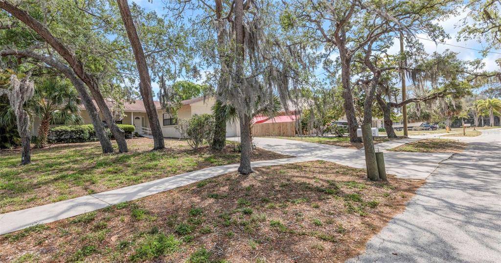 A single-story house with a concrete driveway is surrounded by large, moss-covered oak trees — 753 SEMINOLE BOULEVARD, TARPON SPRINGS, FL