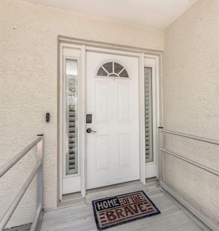 A white front door with sidelights and a welcome mat sits on a porch — 753 SEMINOLE BOULEVARD, TARPON SPRINGS, FL
