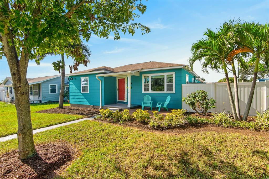 A teal single-story house features a red front door, a large window, and two chairs — 5119 29TH AVENUE N, ST PETERSBURG, FL