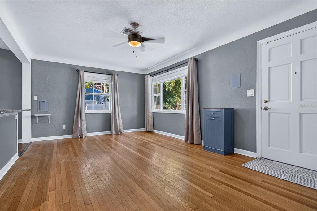 A living room with gray walls, hardwood floors, a ceiling fan, and a white door — 5119 29TH AVENUE N, ST PETERSBURG, FL