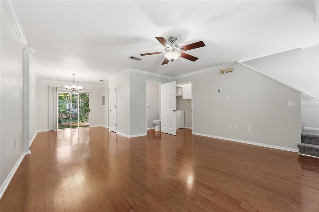 An open-concept living area features hardwood floors, a ceiling fan, and a sliding glass door — 5258 SW 97TH DRIVE, GAINESVILLE, FL