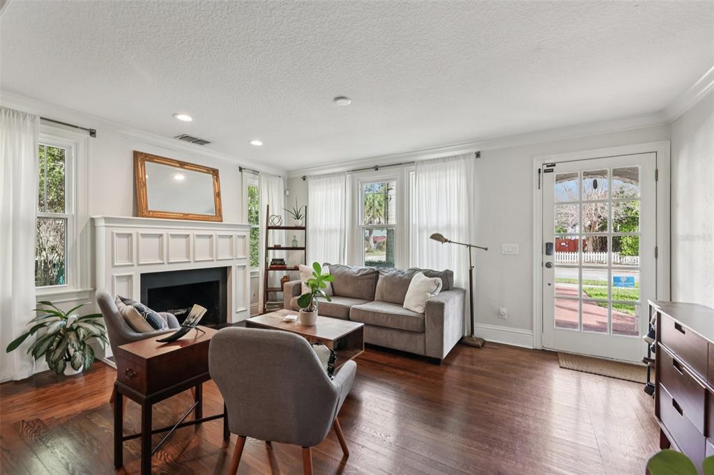 A living room with a fireplace, hardwood floors, a gray sofa, and a glass-paned door — 442 BRIERCLIFF DRIVE, ORLANDO, FL