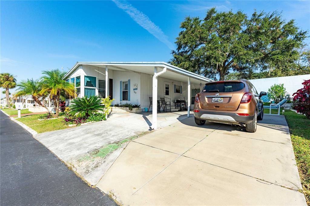 A single-story manufactured home with a carport and a parked SUV in the driveway — 37827 MISSION HILLS AVENUE, ZEPHYRHILLS, FL