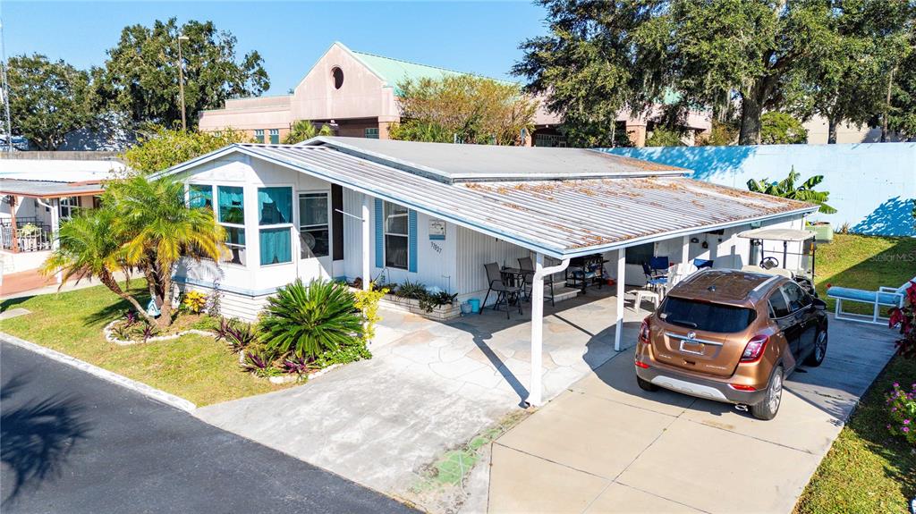 An exterior view of a single-story mobile home with a carport and a parked car — 37827 MISSION HILLS AVENUE, ZEPHYRHILLS, FL