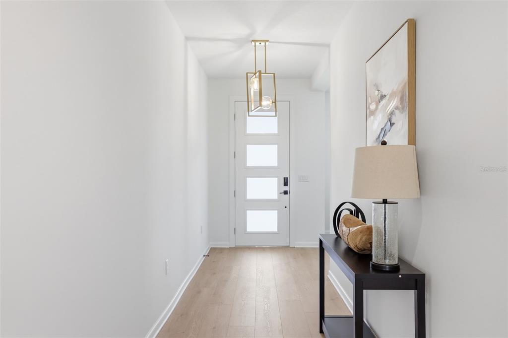 A bright entryway features light wood flooring, a modern pendant light, and a console table — 1595 STONECLIFFF DRIVE, APOPKA, FL