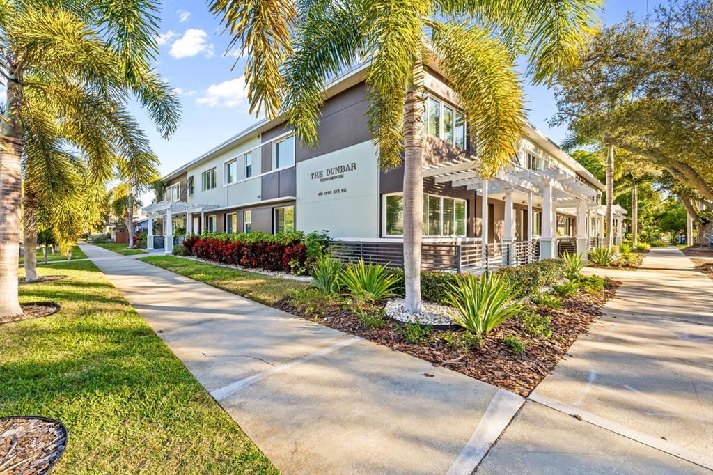 A low-rise condominium building with palm trees and a sidewalk in the foreground — 410 12TH AVENUE NE UNIT 8, ST PETERSBURG, FL