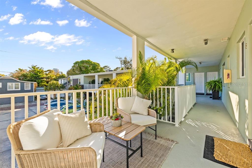 A covered outdoor balcony features wicker chairs, a small table, and a white railing — 410 12TH AVENUE NE UNIT 8, ST PETERSBURG, FL
