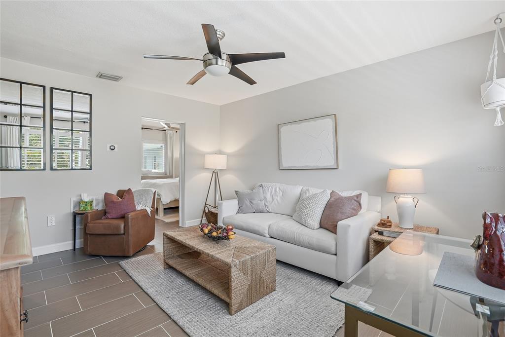 A living room features a white sofa, a woven coffee table, and a brown armchair — 410 12TH AVENUE NE UNIT 8, ST PETERSBURG, FL