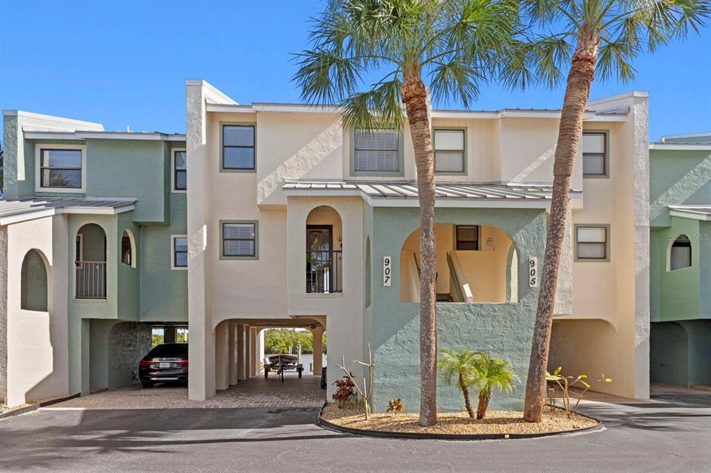 A multi-story townhouse exterior features covered parking, arched entryways, and two tall palm trees — 907 BAHIA DEL SOL DRIVE UNIT 907, RUSKIN, FL