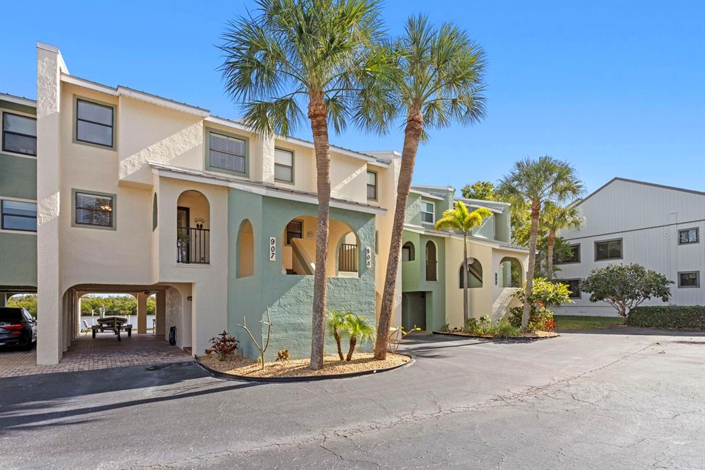 A multi-story residential building with pastel stucco walls, arched entryways, and palm trees — 907 BAHIA DEL SOL DRIVE UNIT 907, RUSKIN, FL