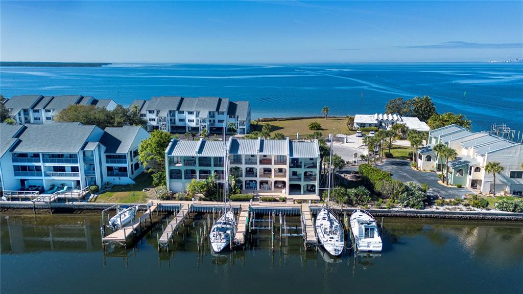 An aerial view shows waterfront condominiums with boat slips and docked vessels on a bay — 907 BAHIA DEL SOL DRIVE UNIT 907, RUSKIN, FL