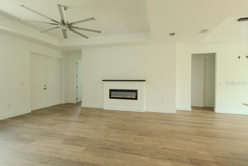 A living room features light wood-look flooring, a tray ceiling with a fan, and a fireplace — 4323 LA FRANCE AVENUE, NORTH PORT, FL
