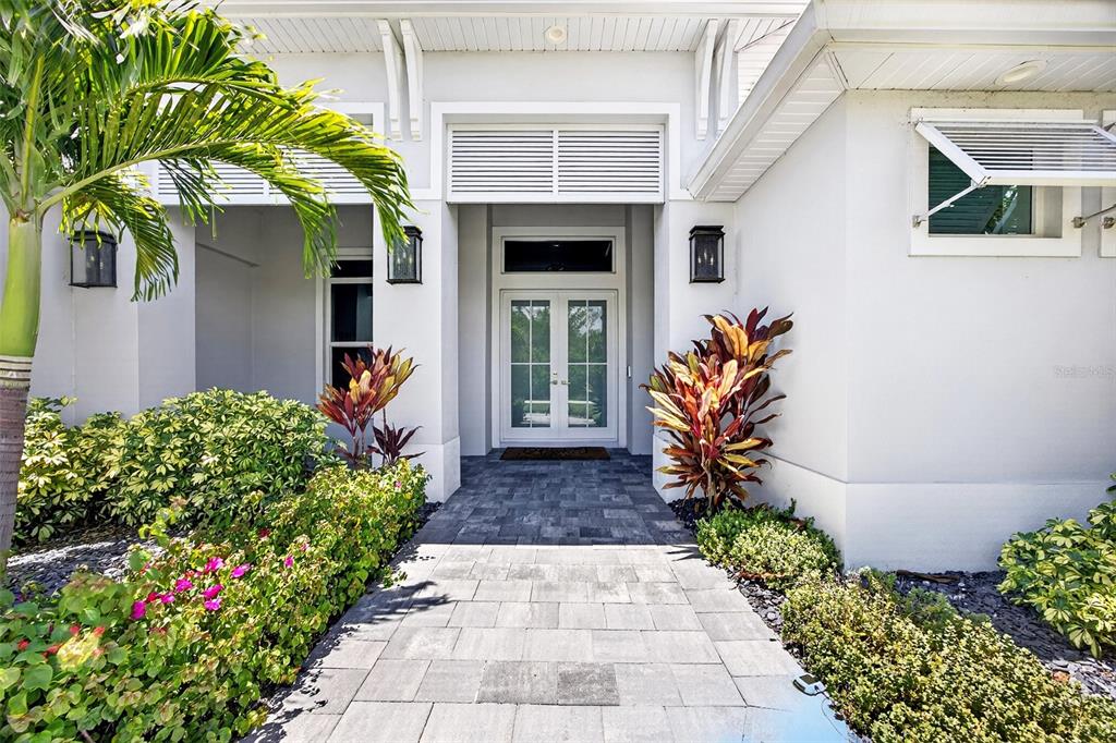 A paved walkway leads to the white double front doors of a modern house — 28116 N MCCALL ROAD, ENGLEWOOD, FL