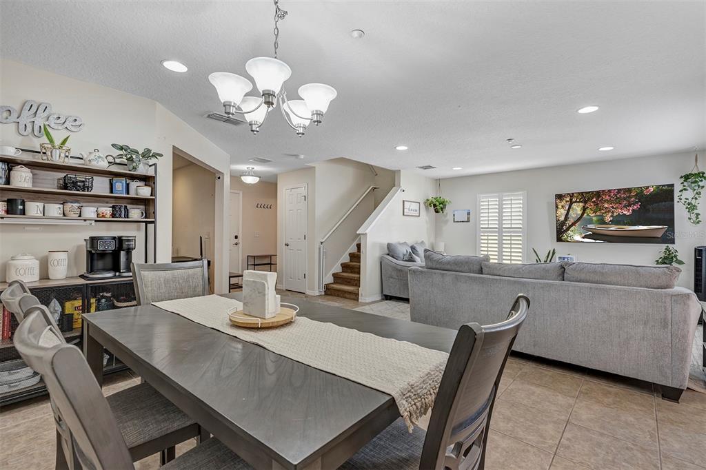 A dining area with a table and chairs opens into a living room with stairs — 13855 GOLDEN RUSSET DRIVE, WINTER GARDEN, FL
