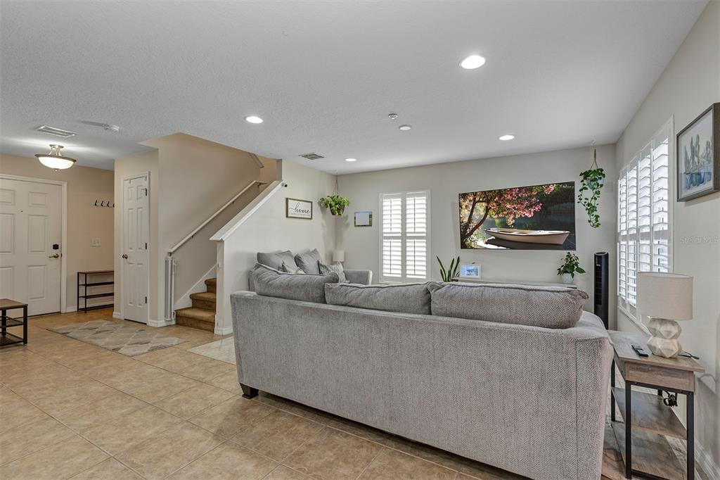A living room features a gray sectional sofa, tile flooring, and a wall-mounted television — 13855 GOLDEN RUSSET DRIVE, WINTER GARDEN, FL