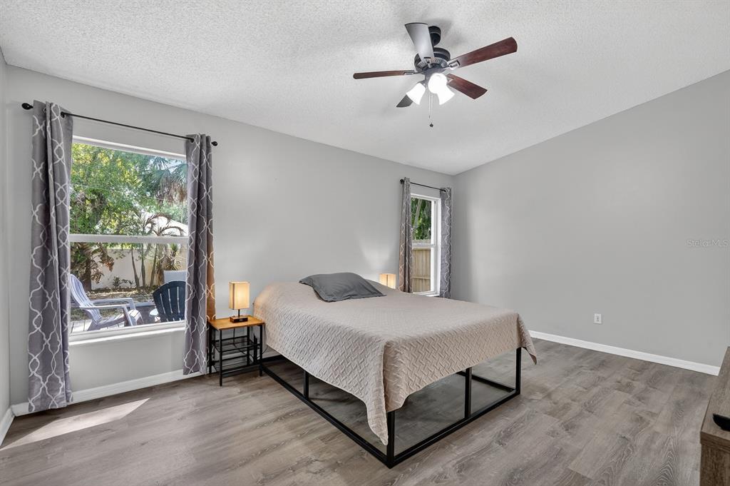 A bedroom features gray walls, wood-look flooring, a bed with a metal frame, and two windows — 3639 OLD HAMMOCK ROAD, PORT ORANGE, FL