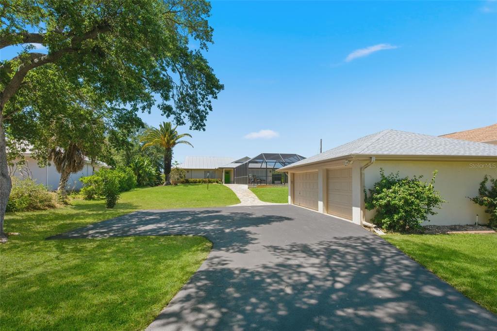 A paved driveway leads to a house with a two-car garage and a screened-in pool — 880 LEMON BAY DRIVE, VENICE, FL