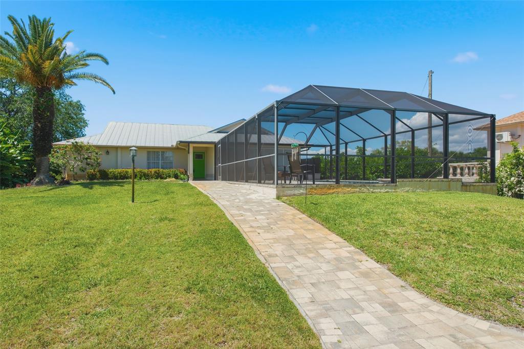 A paved walkway leads to a house with a screened-in pool enclosure and palm tree — 880 LEMON BAY DRIVE, VENICE, FL