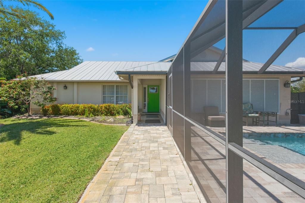 A stone walkway leads to a bright green front door beside a screened-in swimming pool — 880 LEMON BAY DRIVE, VENICE, FL