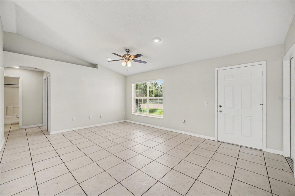A bright room with light-colored tile flooring, a ceiling fan, and a white entry door — 3156 COVENTRY STREET, DELTONA, FL