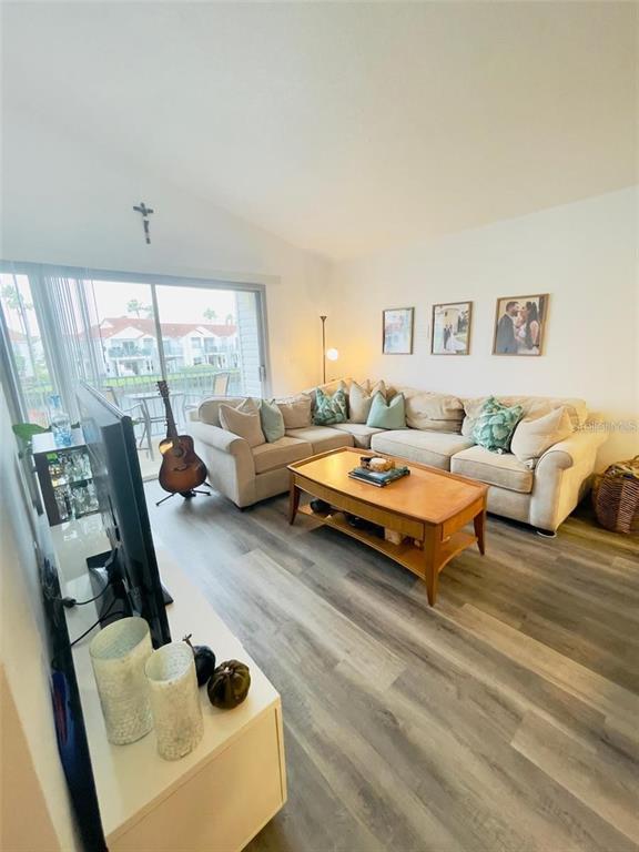 A living room features a large sectional sofa, a wooden coffee table, and wood-look flooring — 2500 WOODGATE BOULEVARD UNIT 203, ORLANDO, FL