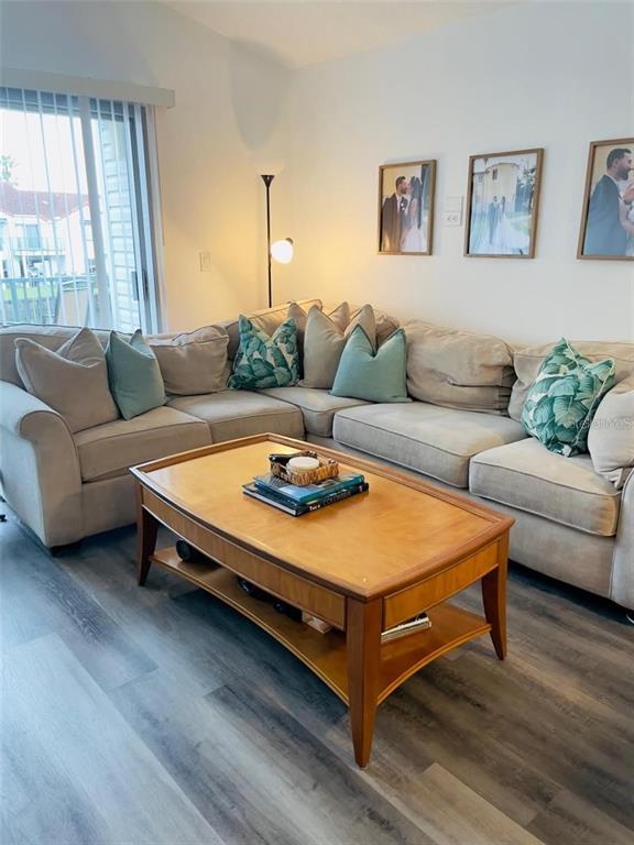 A living room features a beige sectional sofa, a wooden coffee table, and framed wall art — 2500 WOODGATE BOULEVARD UNIT 203, ORLANDO, FL