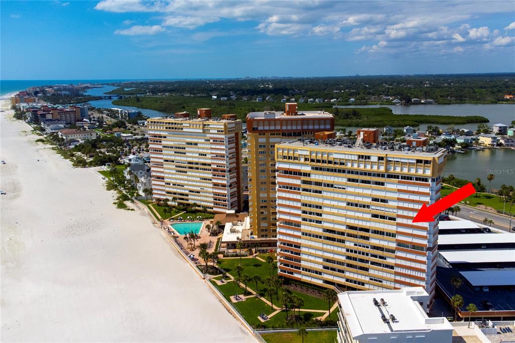 An aerial view shows three tall beachfront apartment buildings with a red arrow pointing toward one — 17900 GULF BOULEVARD UNIT 11C, REDINGTON SHORES, FL
