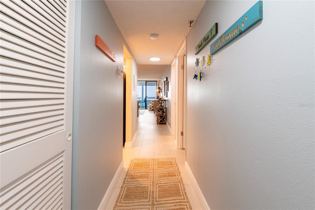 A hallway with white tile floors, a woven rug, and light blue walls leads forward — 17900 GULF BOULEVARD UNIT 11C, REDINGTON SHORES, FL