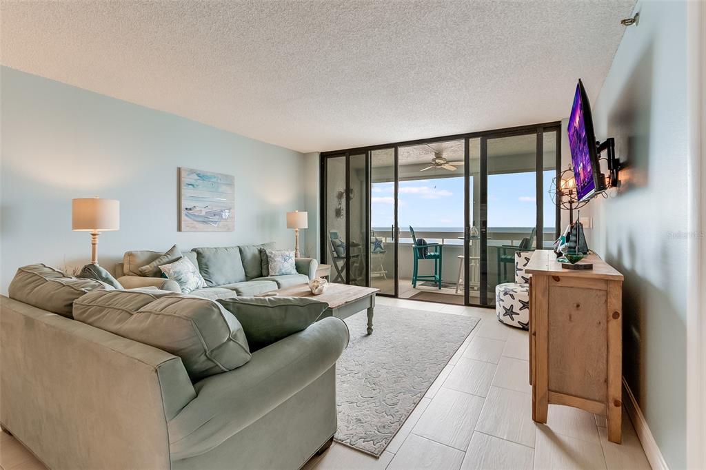 A living room features a light blue sofa, a wooden coffee table, and a balcony view — 17900 GULF BOULEVARD UNIT 11C, REDINGTON SHORES, FL