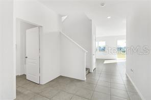 An interior view showing a tiled entryway, a staircase, and an open living area beyond — 911 ALVANLEY COURT, DAVENPORT, FL