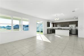 An open-concept kitchen and living area features tile flooring, dark cabinetry, and sliding glass doors — 911 ALVANLEY COURT, DAVENPORT, FL