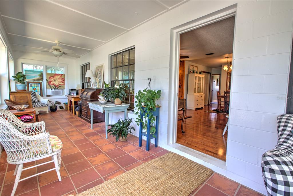 A sunroom with terracotta tile flooring, white block walls, and a view into the home — 825 E 23RD AVENUE, NEW SMYRNA BEACH, FL