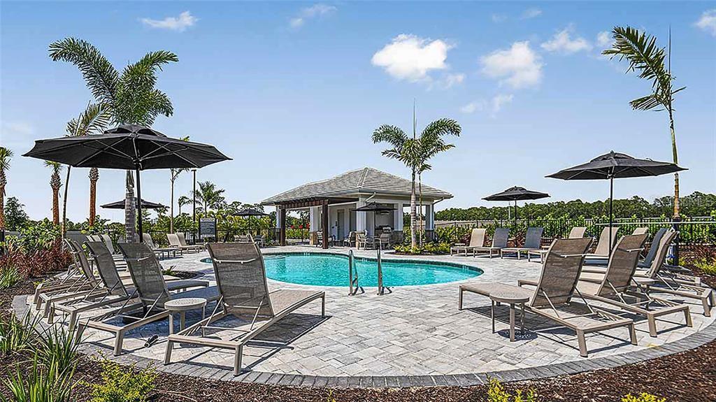 A swimming pool with lounge chairs and umbrellas sits in front of a small pavilion — 8500 LUNAR SKYE STREET, SARASOTA, FL