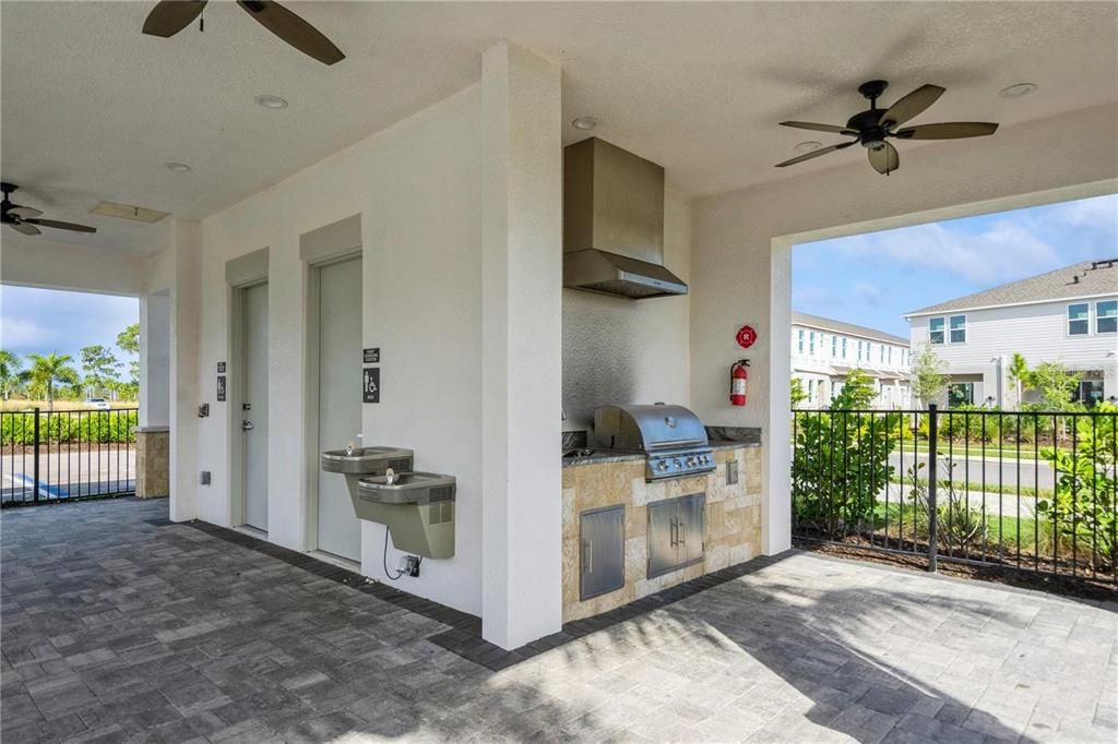 An outdoor kitchen area features a stainless steel grill, stone base, and a water fountain — 8500 LUNAR SKYE STREET, SARASOTA, FL