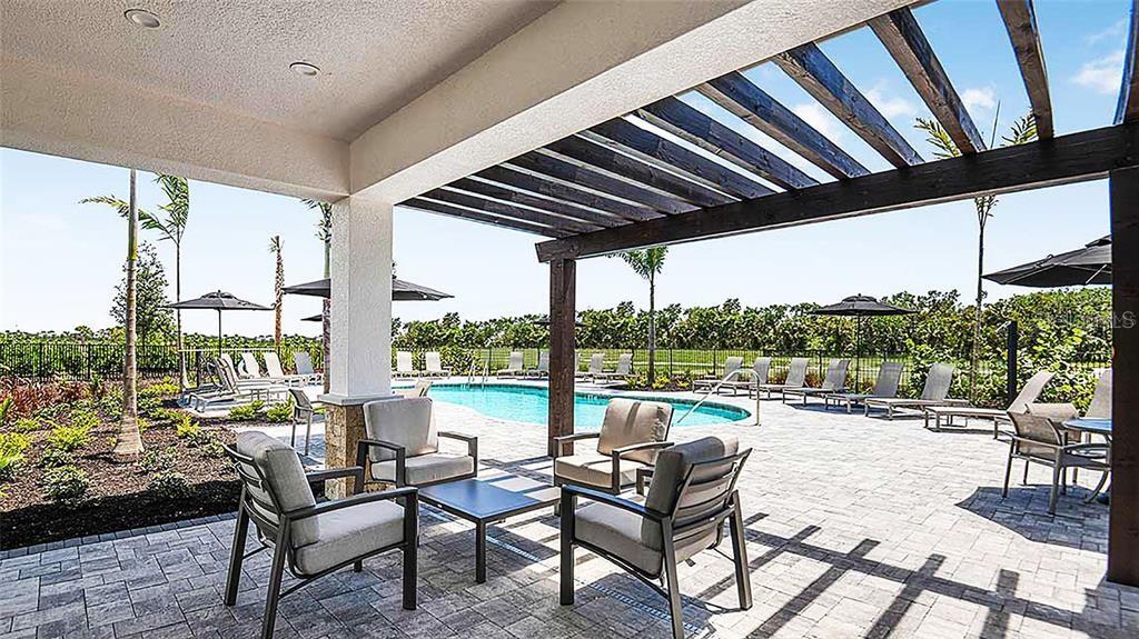 A covered patio with a pergola overlooks a swimming pool and landscaped outdoor seating area — 8500 LUNAR SKYE STREET, SARASOTA, FL