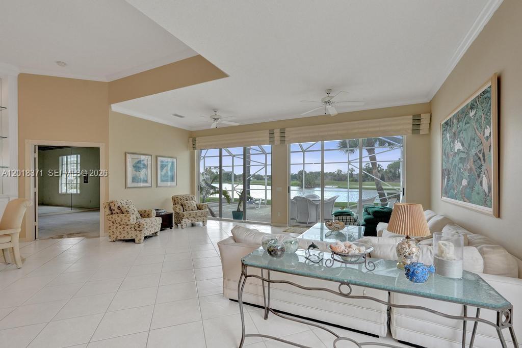 A living room with tile floors, white sofas, and large windows overlooking a lake — 7968 SE Double Tree Dr, Hobe Sound FL 33455, HOBE SOUND, FL