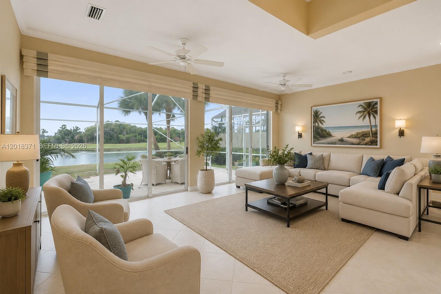 A bright living room features a sectional sofa, two armchairs, and sliding glass doors overlooking water — 7968 SE Double Tree Dr, Hobe Sound FL 33455, HOBE SOUND, FL