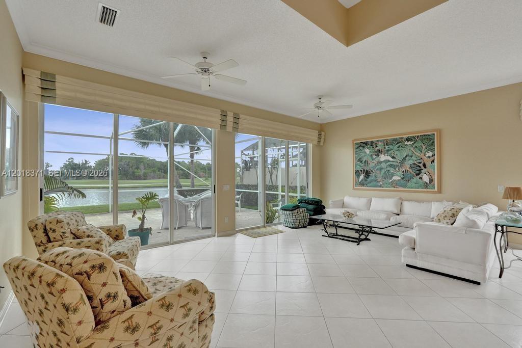 A spacious living room features white tile floors, a large sectional sofa, and sliding glass doors — 7968 SE Double Tree Dr, Hobe Sound FL 33455, HOBE SOUND, FL